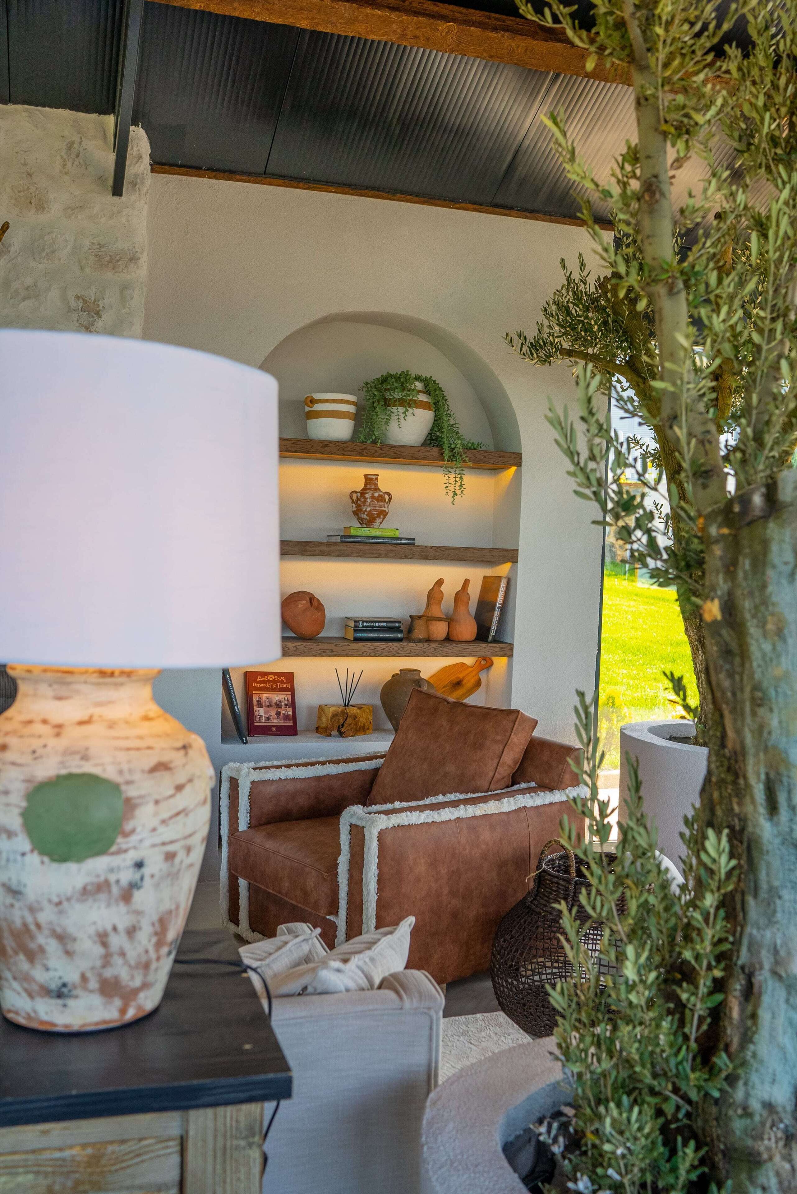 Un espacio de sala acogedor con un sofá, una lámpara y estanterías decoradas con objetos ornamentales.