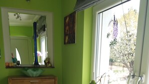 Ein Badezimmer mit Holzschrank, Spiegel und Fenster mit Blick auf Bäume.