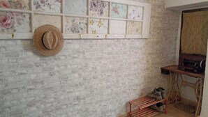 Una habitación con pared de ladrillo, un banco de madera, un sombrero y una máquina de coser.