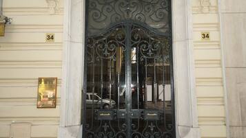 A building entrance with a black ornate gate, a balcony with white balustrades, and the number 34 on the wall.