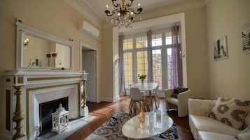 A living room with a fireplace, a chandelier, a dining area, and a sofa.