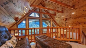 Ein Loft-Zimmer mit Holzboden, einem großen Fenster, einem Ledersofa und einer Holzbank.