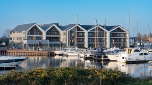 A marina with modern buildings and boats docked. - Breathtaking Penthouse Views (Kamperland)