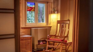 Ein gemütliches Zimmer mit einem Holzschaukelstuhl, einem Kamin und einem Fenster mit einem Buntglasdekor.