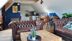 A loft-style living room with a brown leather sofa, a wooden coffee table with a plant, and a dining area in the background. - Shed 57b in an old flour mill in Haulerwijk (Haulerwijk)