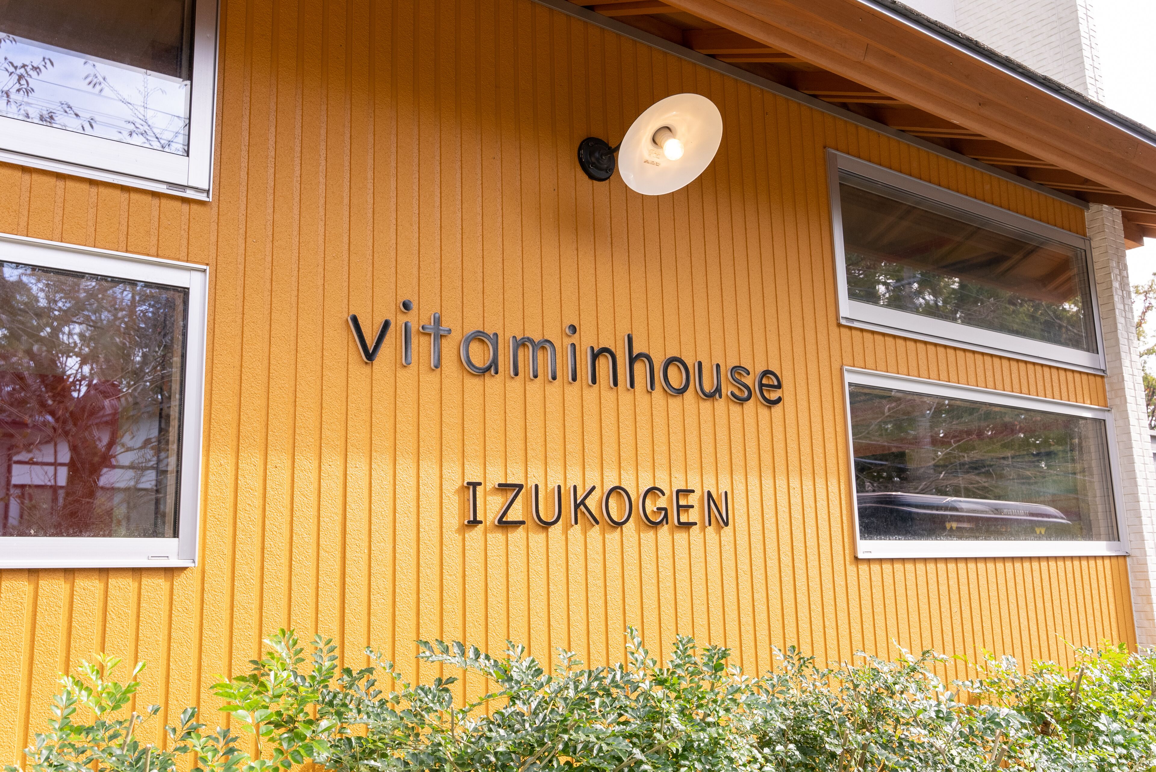 Un bâtiment avec une enseigne « Vitaminhouse IZUKOGEN » sur un mur jaune.