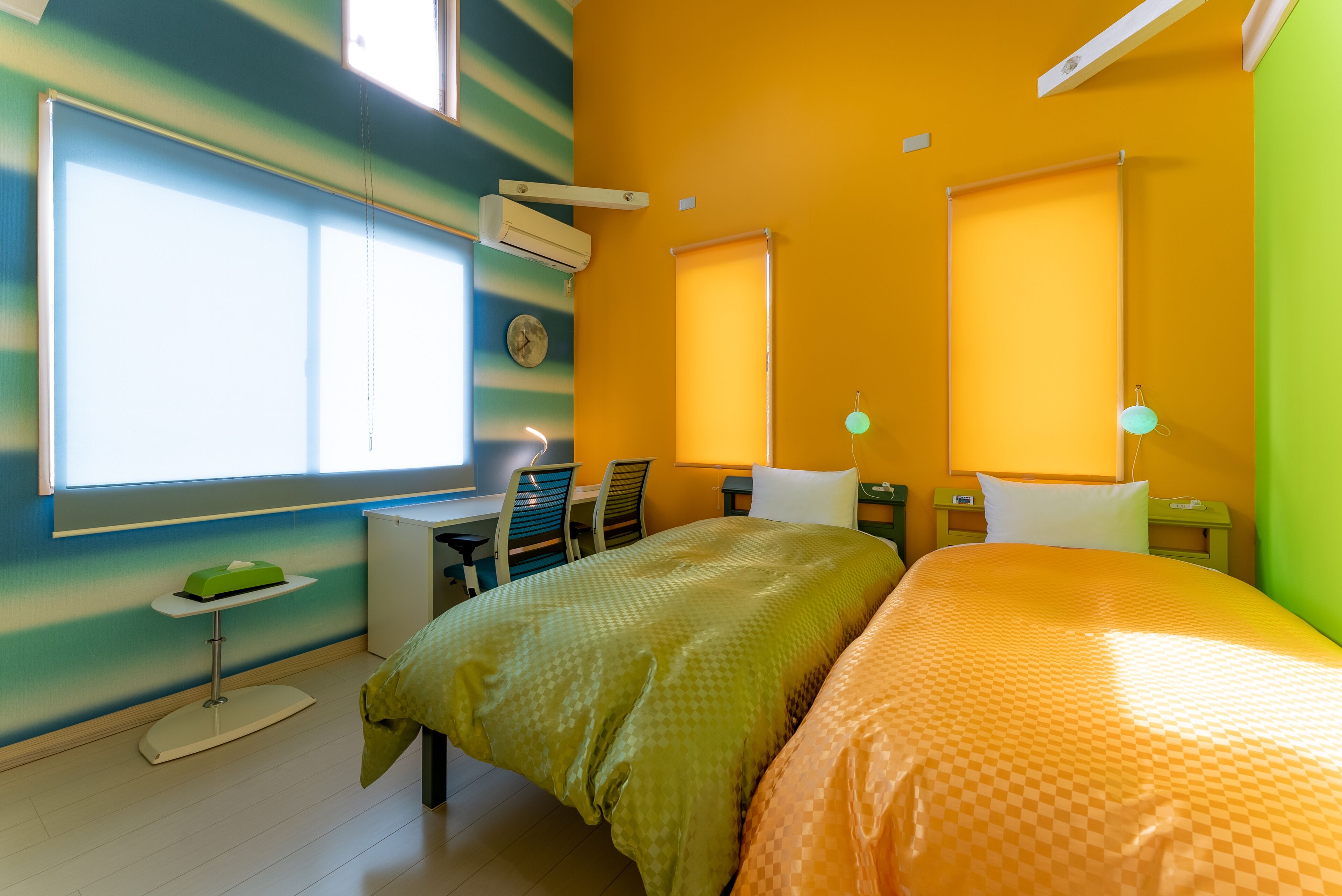 A hotel room with a bed, a desk, a chair, a small table, and a window.