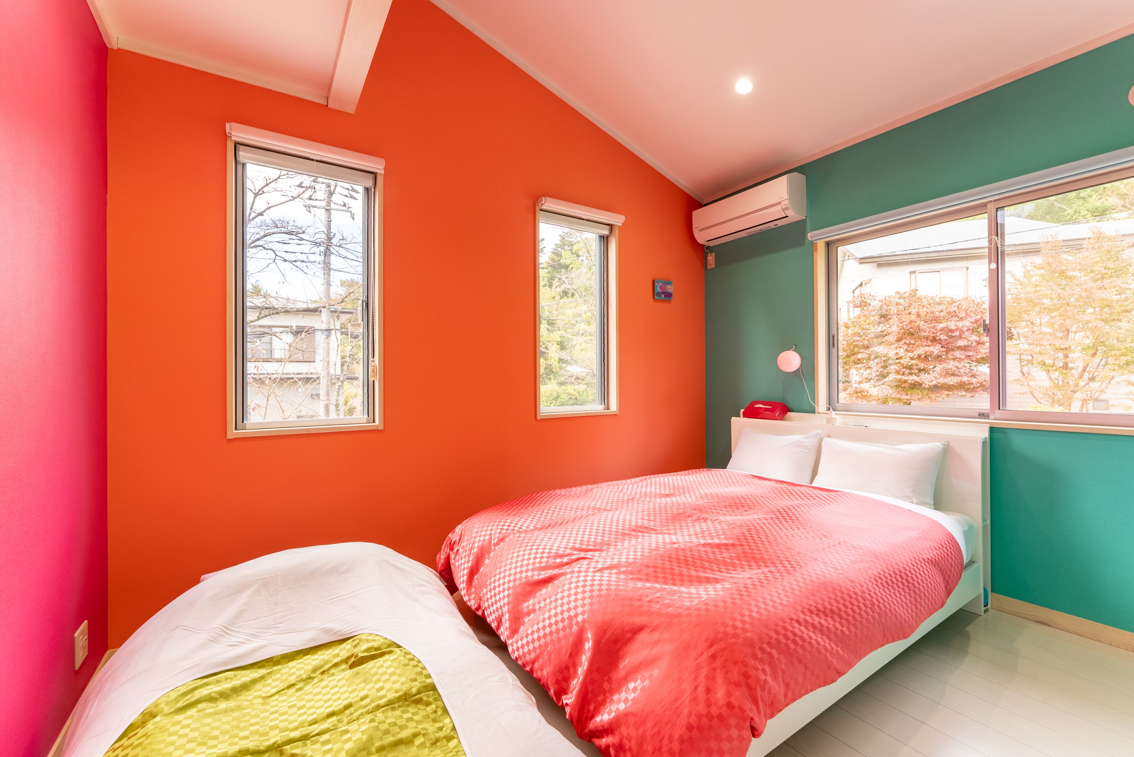 A bedroom with two beds, a window, and an air conditioning unit.