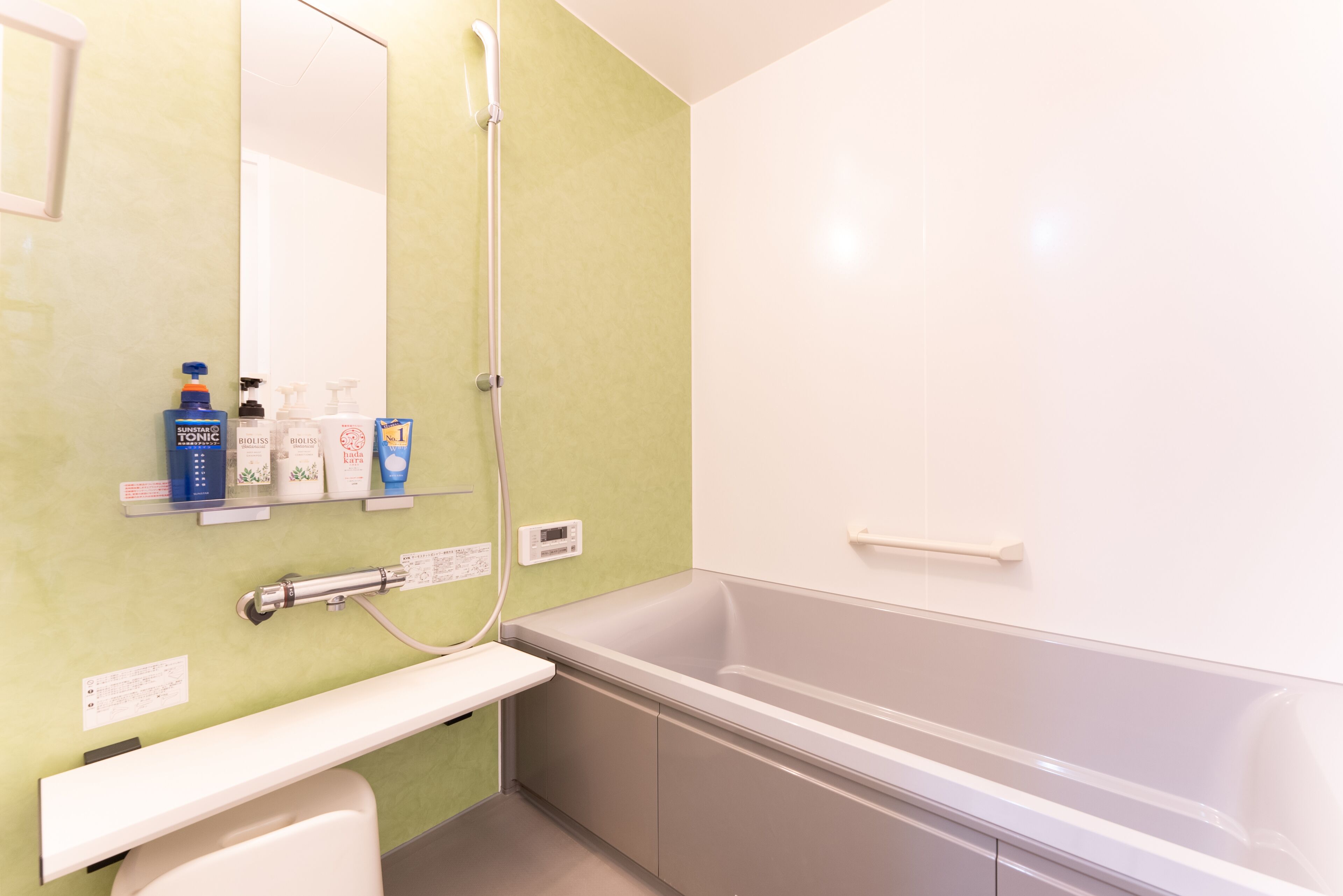 A bathroom with a bathtub, a shower, and a toilet. There are toiletries on a shelf.
