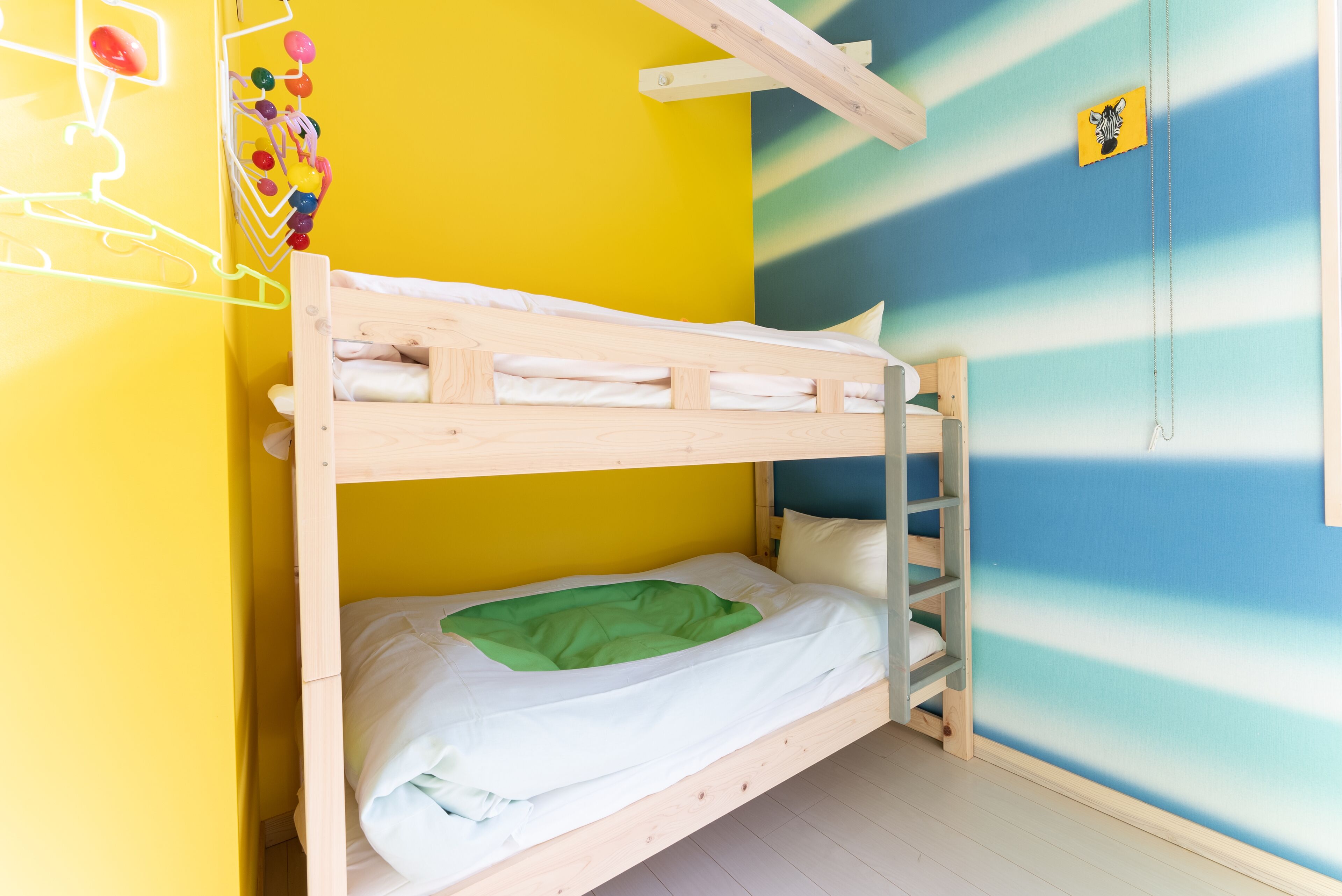 A bunk bed in a room with a yellow and blue striped wall.