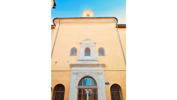 Un edificio con facciata gialla, una finestra ad arco centrale e un piccolo campanile.