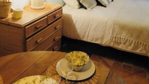Una camera da letto con un letto, un comodino, una lampada e un tavolo da pranzo con piatti.