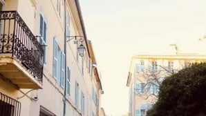 Una stretta via fiancheggiata da edifici, con balconi e cielo sereno.