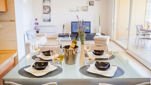 Une table à manger dressée pour six personnes, avec des verres à vin, une bouteille de champagne et un vase rempli de fleurs.