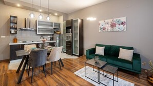Une cuisine moderne avec un coin repas, un canapé vert et un tableau accroché au mur.