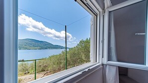 A window with a view of a lake, a mountain, and a green fence. - Beautiful Villa with private pool and sea view (Vela Luka)