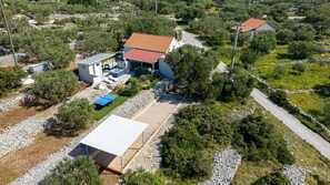 A house with a swimming pool, a tennis court, and a stone pathway.