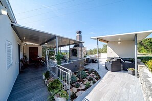 Eine moderne Außenpatio mit Kamin aus Stein, Sitzgelegenheit und überdachtem Gang.
