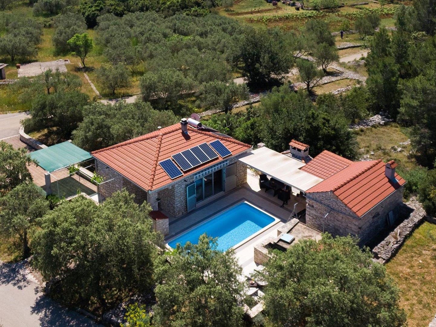 A house with a swimming pool, solar panels, and a stone exterior.