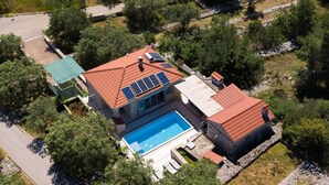 Une maison avec une piscine, des panneaux solaires et un chemin en pierre.