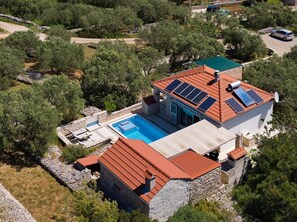 Een villa met een zwembad, zonnepanelen en een stenen gevel.