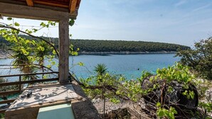Una pergola in legno affacciata su un mare tranquillo con una costa boscosa.