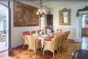 A dining room with a large table set for six, surrounded by wicker chairs, a chandelier, and a large landscape painting on the wall. - Unique hilltop villa in Provence, stunning private pool, 6+bdrms + optional gite (Beaucaire)