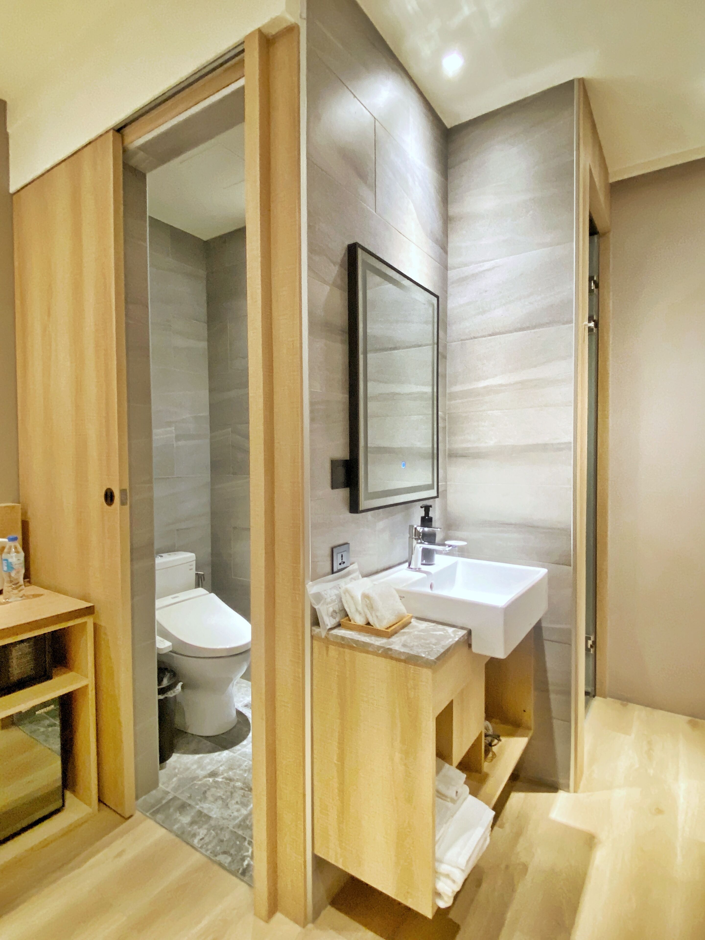 A modern bathroom with a wooden vanity, a white sink, and a toilet.
