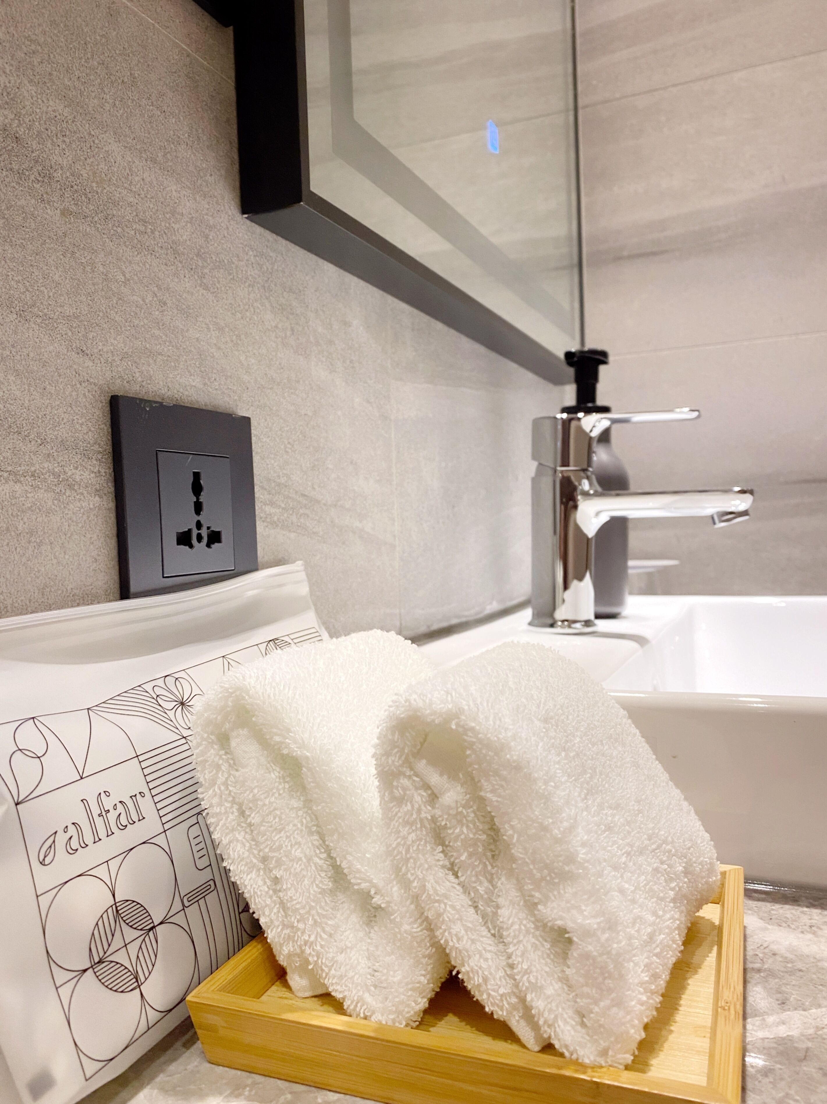 A bathroom with a white bathtub, a towel rack with a folded towel, and a wall-mounted light switch.