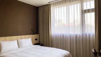 A hotel room with a large bed, a headboard, a bedside table, and a chair.