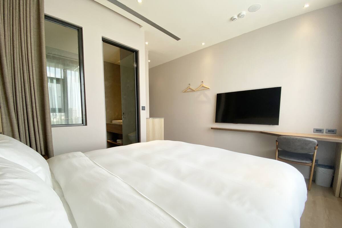 Une chambre d’hôtel avec deux grands lits, une télévision, un bureau et un miroir.