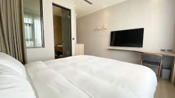 A hotel room with two large beds, a TV, a desk, and a mirror.