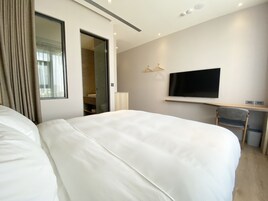 Habitación de hotel con dos camas grandes, televisión, escritorio y espejo.