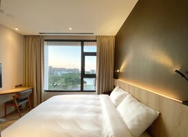 Una habitación de hotel con una cama grande, un escritorio y una ventana con vistas a la ciudad.