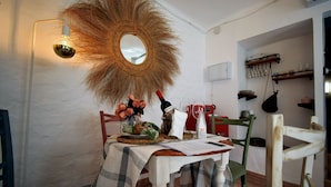 A dining area with a table set for two, a mirror, and a hanging light fixture. - El Orgullo rural house, with terrace and impressive views of the Bailón Canyon. (Zuheros)