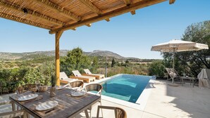 Un espace aménagé au bord de la piscine, avec une table dressée pour les repas, des chaises longues et un parasol.