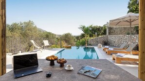 Un espace aménagé au bord de la piscine, avec des chaises longues, un ordinateur portable et des articles pour le petit-déjeuner.