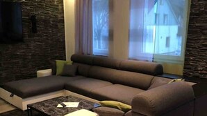 A modern living room with a sectional sofa, a coffee table, and a stone accent wall. - TOP APARTMENT- 2 floors - 100 m² - up to 10 people (Dortmund)