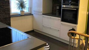 A modern kitchen with white cabinets, a black countertop, and a built-in oven. - TOP APARTMENT- 2 floors - 100 m² - up to 10 people (Dortmund)