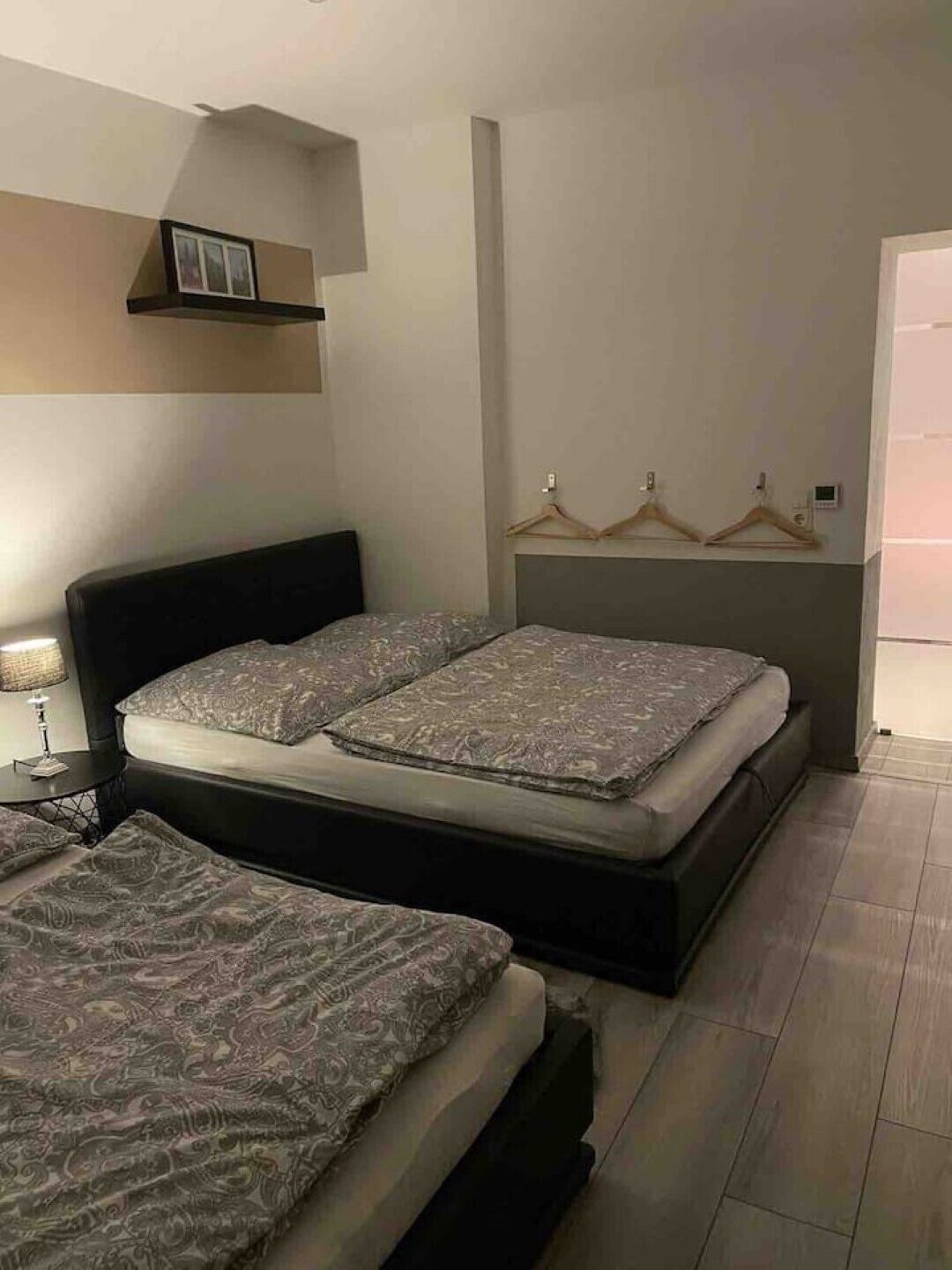 Une chambre à coucher avec un lit double, une table de chevet et une étagère murale avec des supports pour suspendre des vêtements.