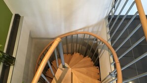 A spiral staircase with a wooden handrail and metal balusters, leading to a landing with a black tiled floor. - TOP APARTMENT- 2 floors - 100 m² - up to 10 people (Dortmund)