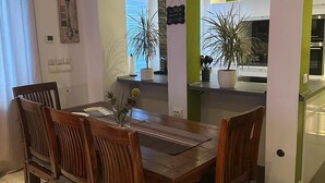 A dining area with a wooden table and chairs, potted plants, and a view into the kitchen. - TOP APARTMENT- 2 floors - 100 m² - up to 10 people (Dortmund)