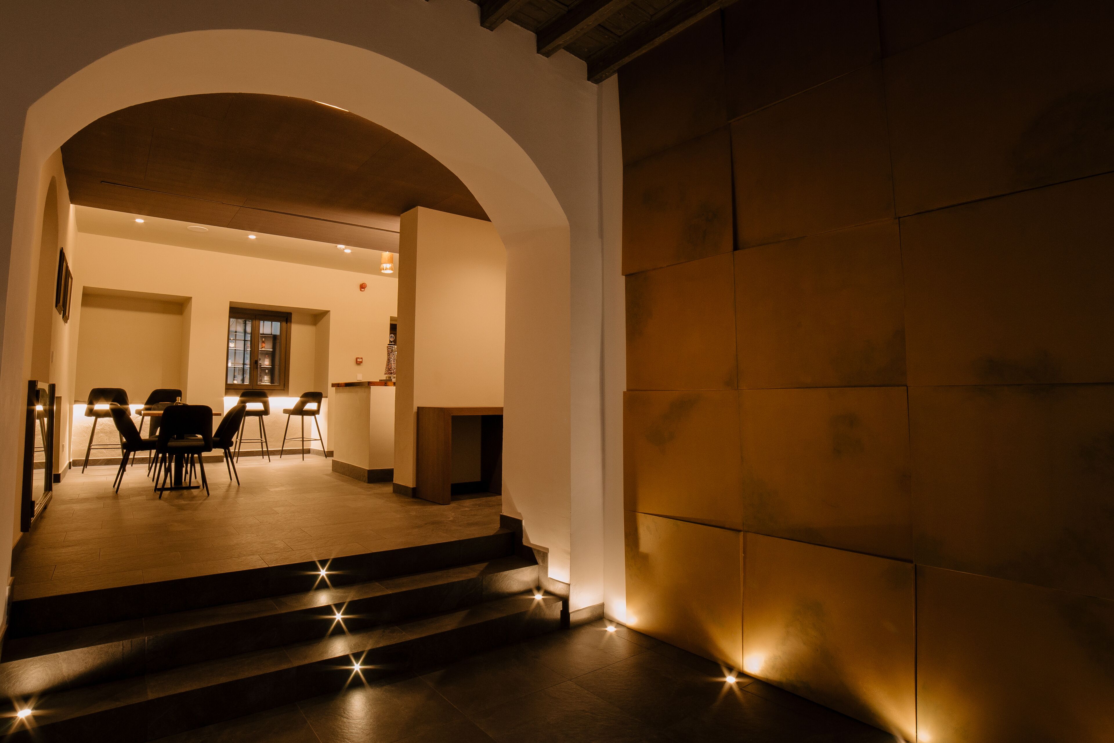 A hotel lobby with a staircase leading to a dining area, a reception desk, and a view of the interior.