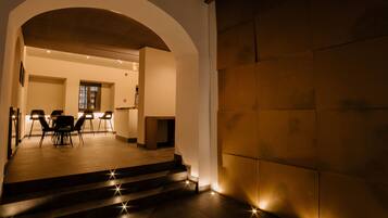 A hotel lobby with a staircase leading to a dining area, a reception desk, and a view of the interior.