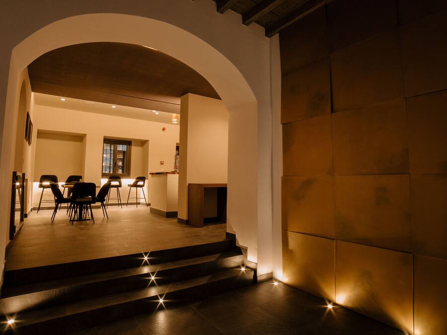 A hotel lobby with a staircase leading to a dining area, a reception desk, and a view of the interior.