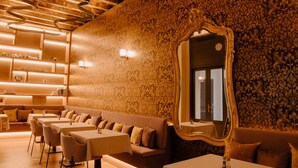 A restaurant with wooden ceiling beams, patterned wallpaper, and tables with chairs. - Casa del Cardenal (Córdoba)