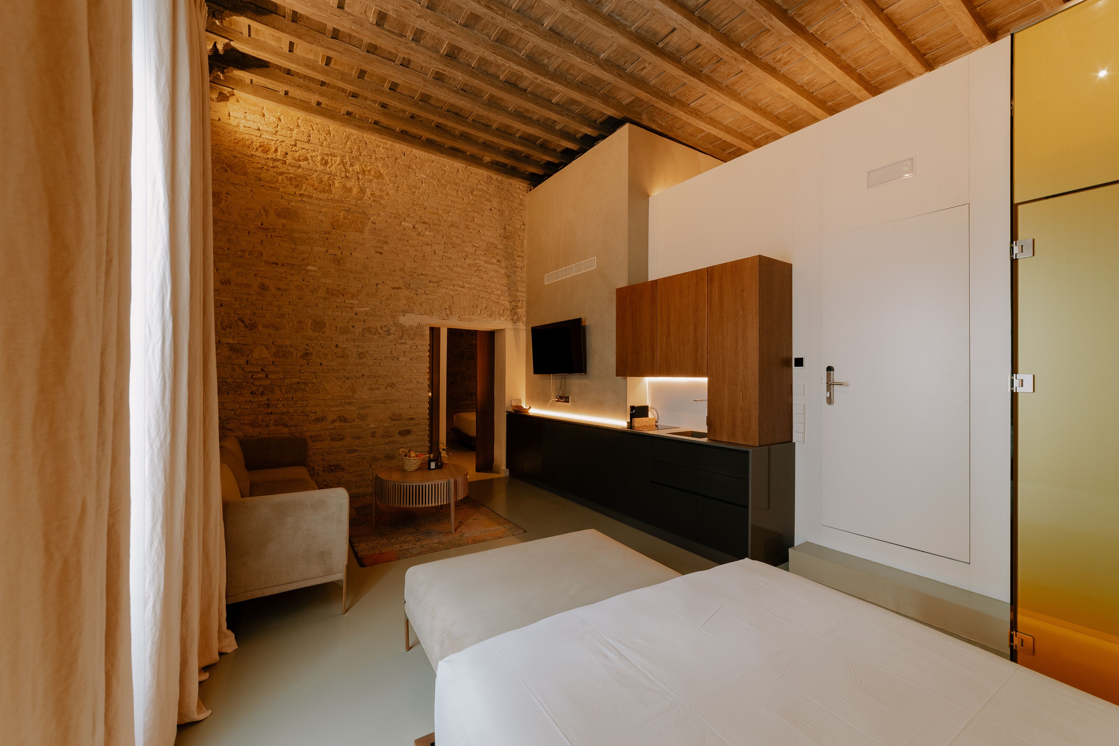 A room with a bed, a chair, a TV, and a wooden cabinet.
