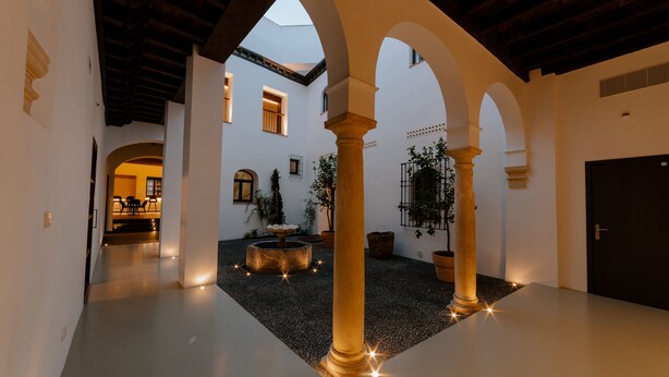 A spacious courtyard with a fountain, columns, and a door. - Casa del Cardenal (Córdoba)