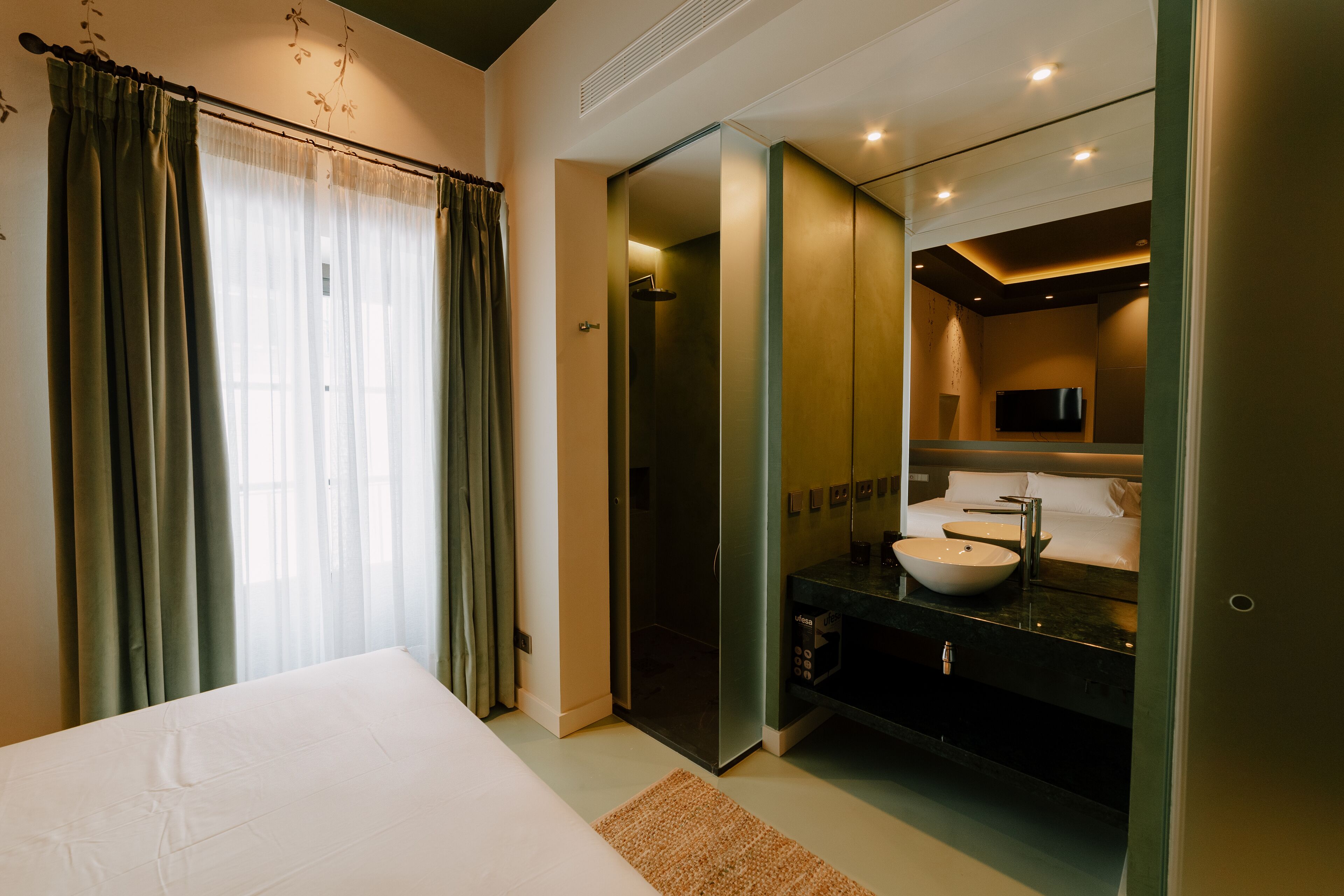 Una habitación de hotel con una cama, un baño con lavabo y ducha.
