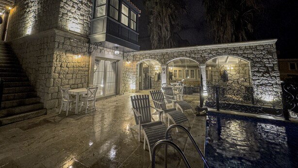 A stone building with a balcony, outdoor seating, and a pool area at night. - Fedora Alacati (Cesme)